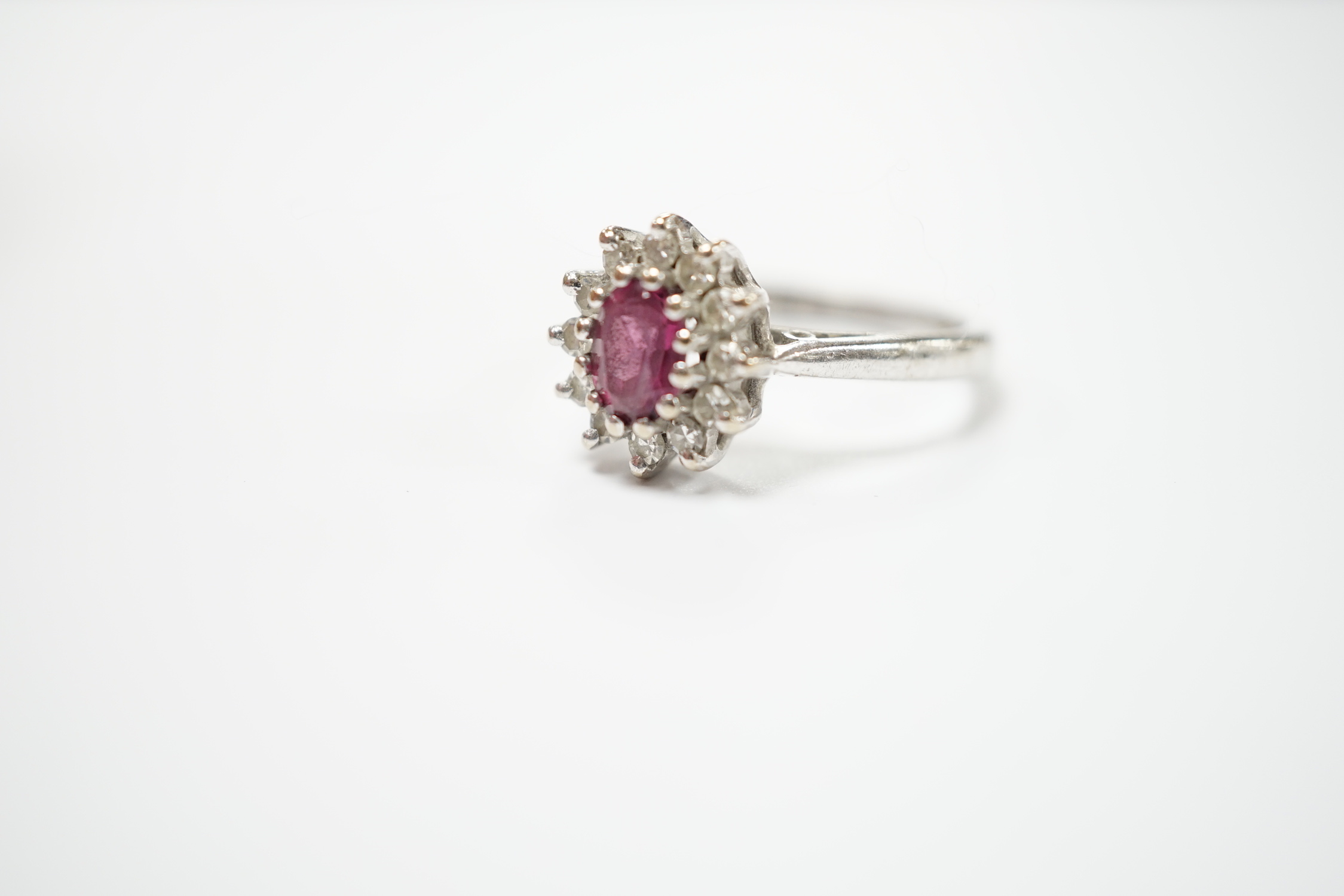 A modern 18ct white gold, ruby and diamond set oval cluster ring, size M/N, gross weight 5.2 grams.